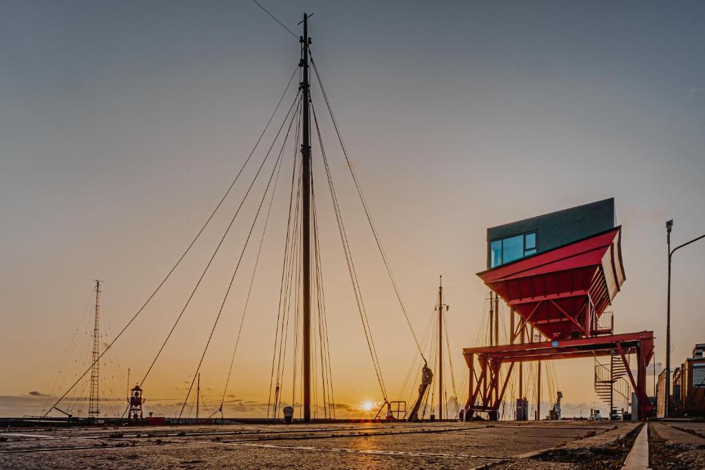 łódź żaglowa siedząca na plaży o zachodzie słońca w obiekcie Slapen in een Trechter w mieście Harlingen