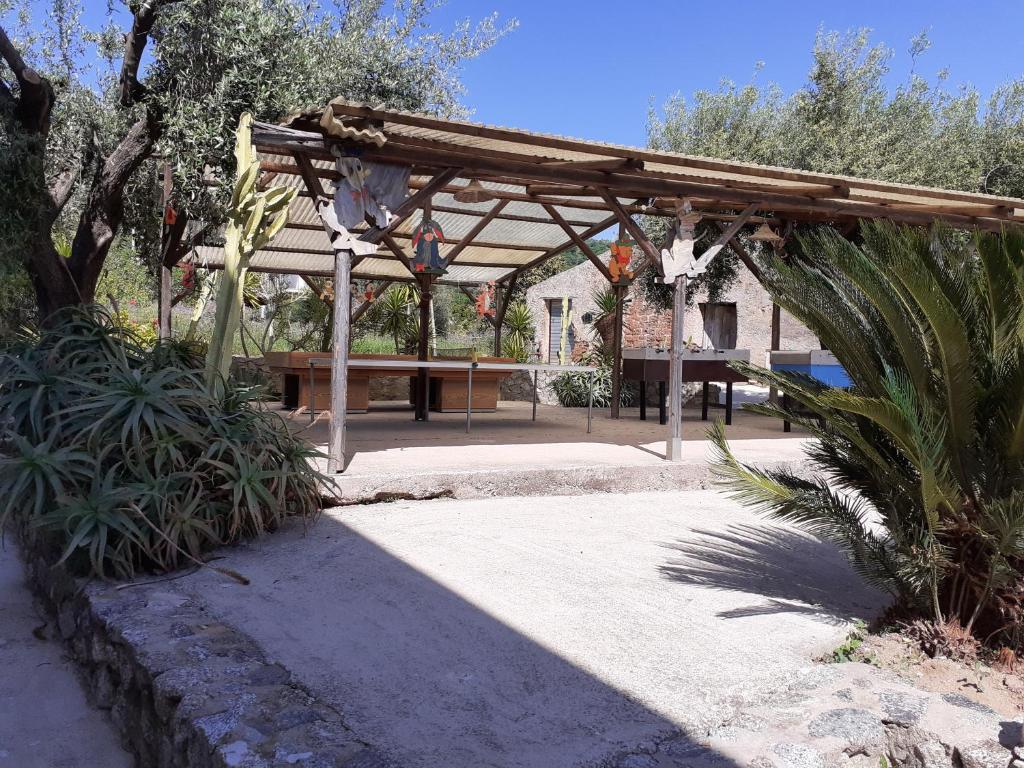a wooden pergola with a table in a park at agriturismo heaven in Capo Vaticano