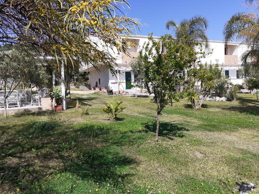 a yard with trees and a building in the background at agriturismo heaven in Capo Vaticano