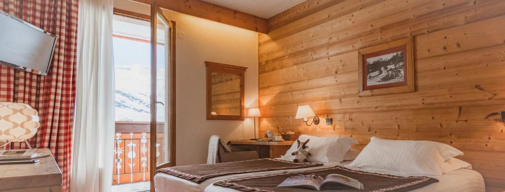 a bedroom with a bed with a wooden wall at Hôtel Le Sherpa Val Thorens in Val Thorens