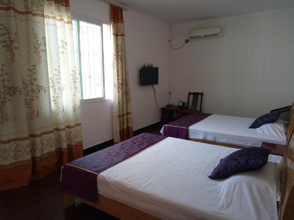 a hotel room with two beds and a window at Shell Haikou Xiuying District Hainan University Hotel in Haikou