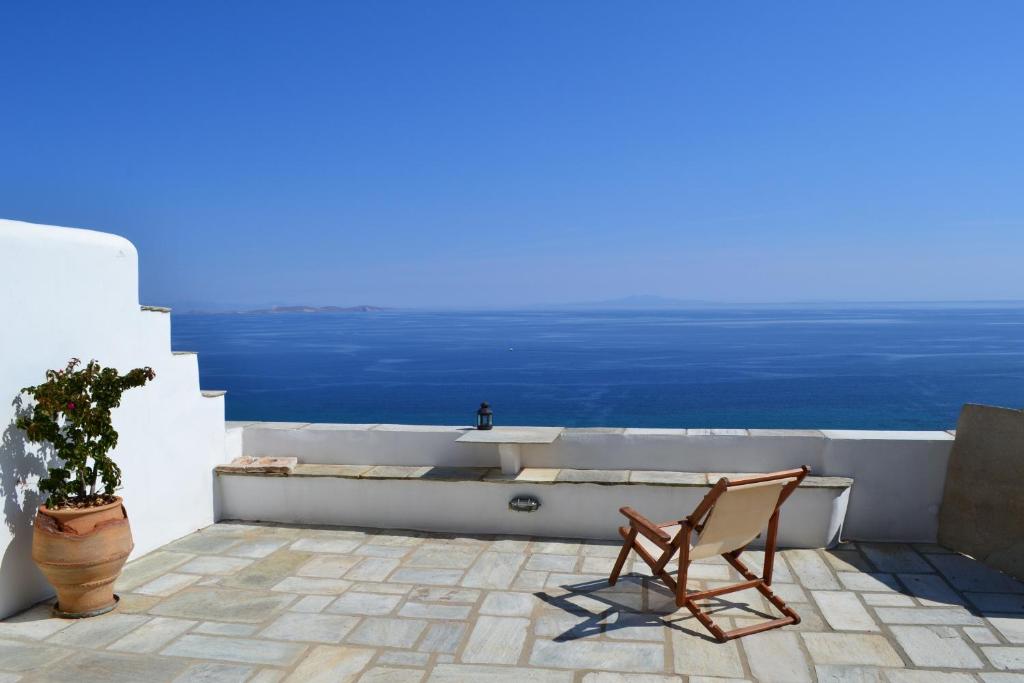 a chair and a tub on a balcony with the ocean at Villa Ioanna Tinos in Kionia