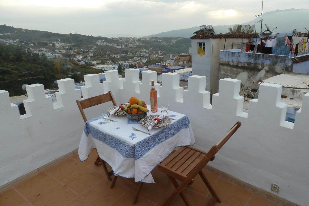una mesa y sillas en un balcón con vistas en Dar Anneke, en Chefchaouen