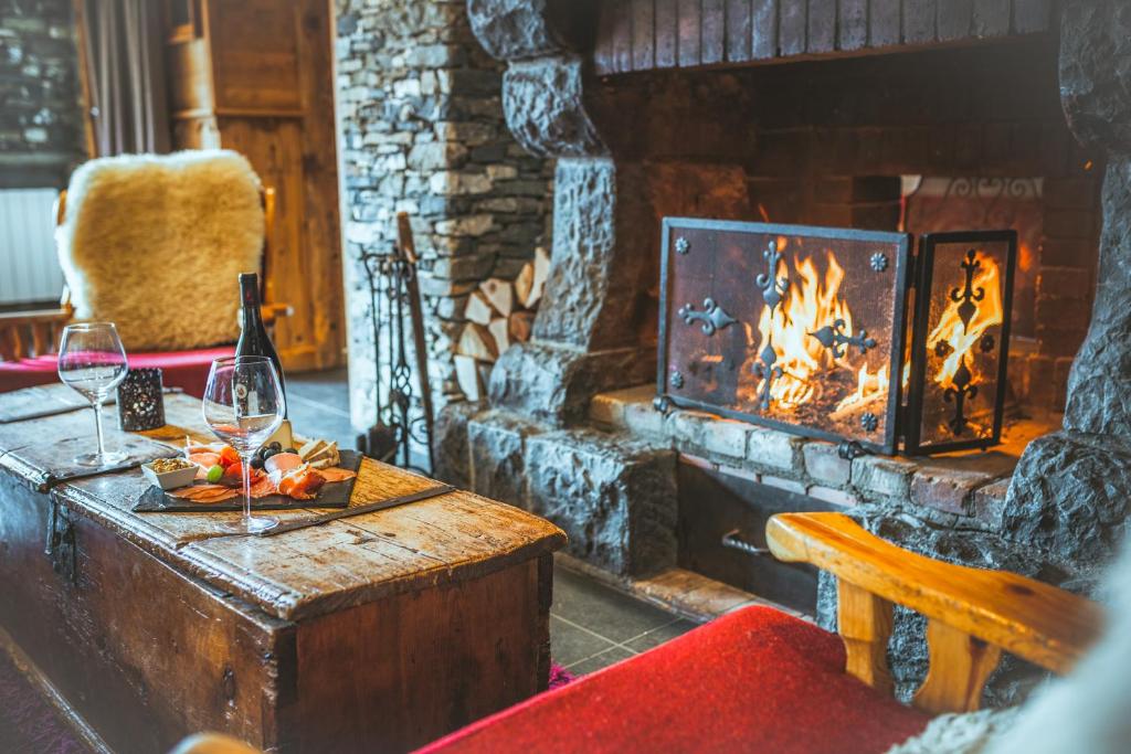 a living room with a fireplace and a table with wine glasses at Hôtel Le Sherpa Val Thorens in Val Thorens