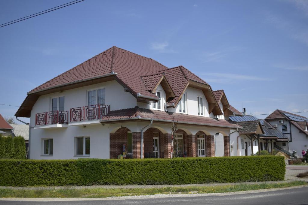 a white house with a brown roof at Főnix Apartmanház in Nagypáli