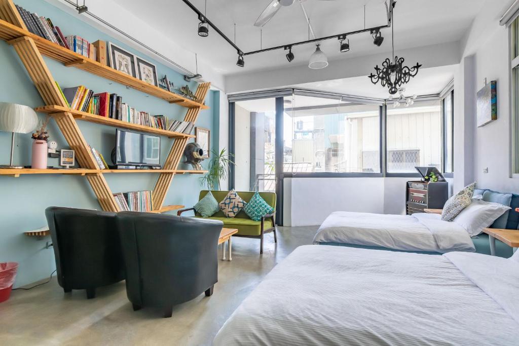 a room with two beds and a chair and bookshelves at Art Station x Residence in Tainan