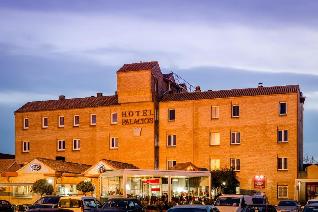 un gran edificio con coches estacionados frente a él en Hotel Palacios en Alfaro