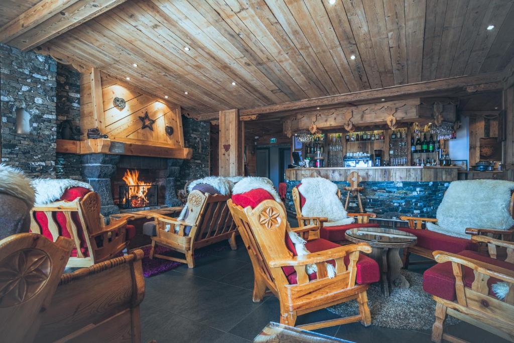 a bar with rocking chairs and a fireplace at Hôtel Le Sherpa Val Thorens in Val Thorens