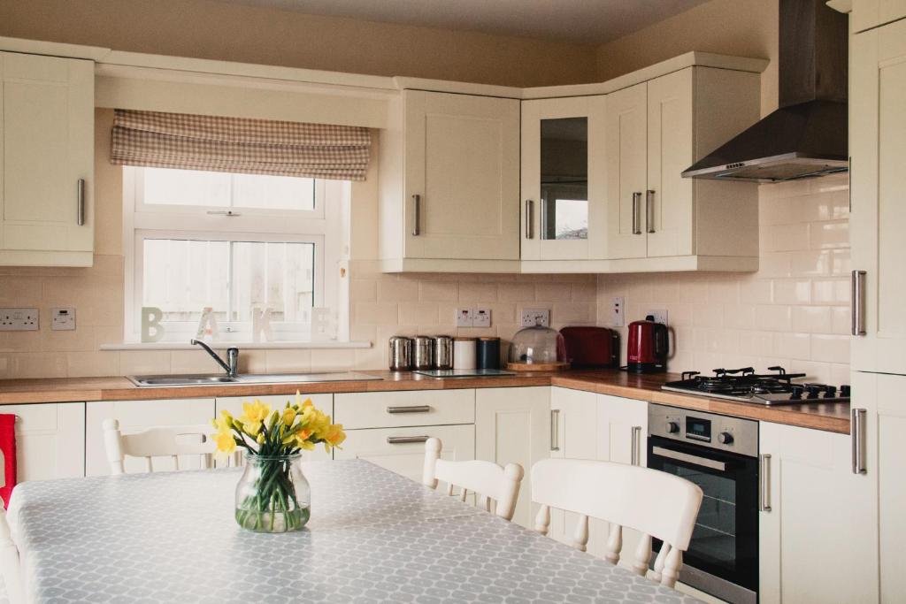 una cocina con armarios blancos y una mesa con flores amarillas en corby house en Ardara
