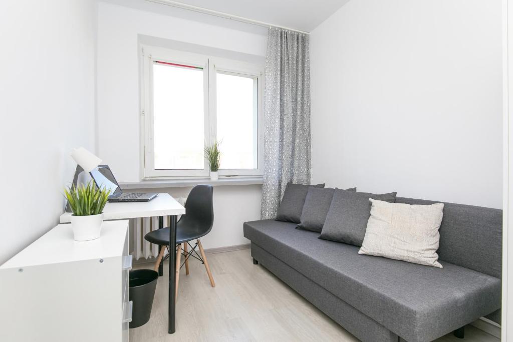 a living room with a couch and a desk with a computer at Rooms4Less in Gdańsk