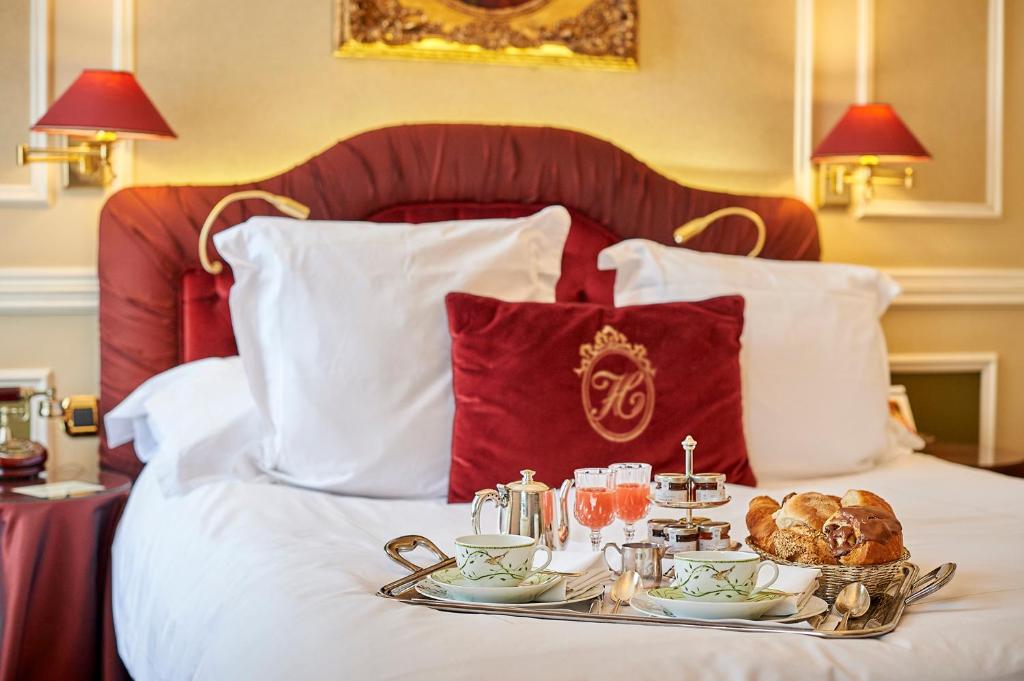 a tray with food and drinks on a bed at Relais & Châteaux Hotel Heritage in Bruges