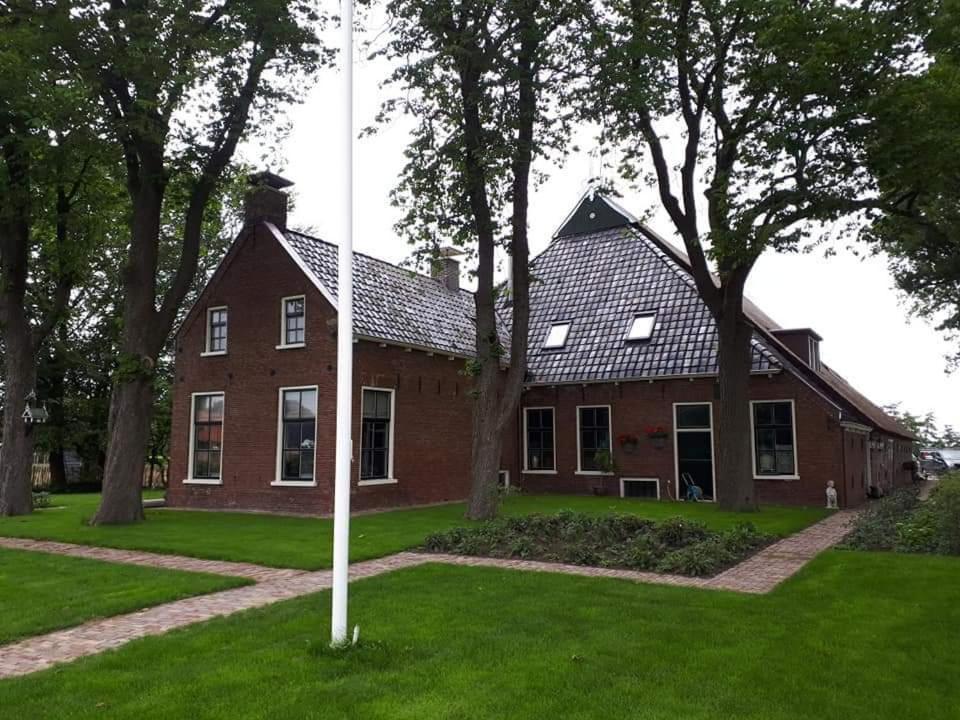 a red brick house with a pole in the grass at B&B De Herenboer in Opeinde