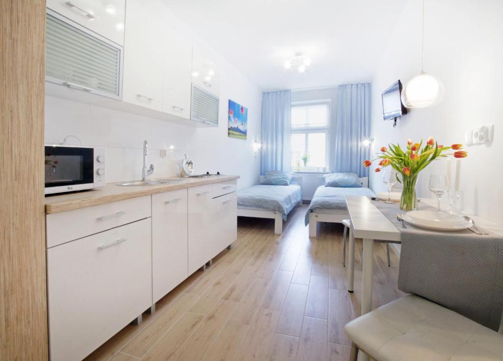 cocina y sala de estar con armarios blancos y mesa en Duarte Apartamenty, en Wroclaw