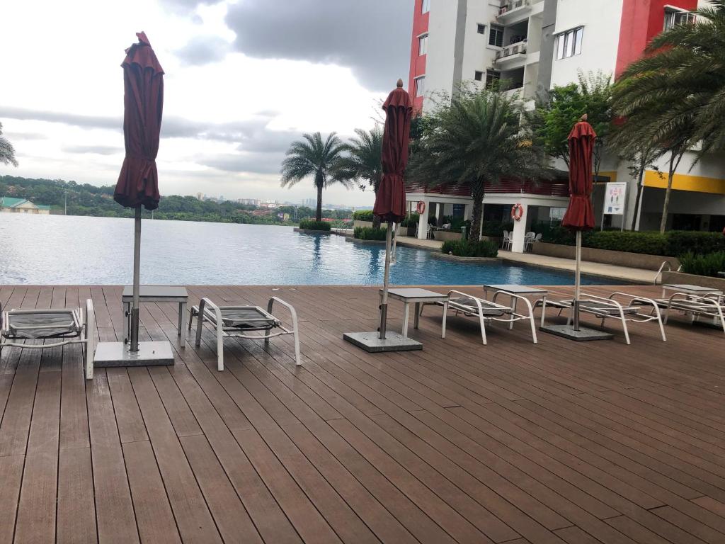 een terras met stoelen, tafels en parasols naast een zwembad bij Main Place Resort Family Suite in Subang Jaya