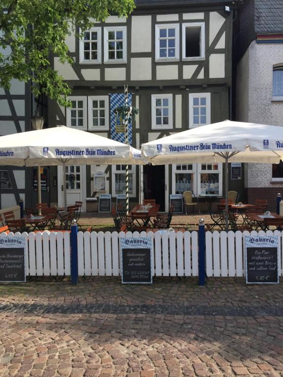 zwei Sonnenschirme, Tische und Stühle vor einem Gebäude in der Unterkunft Bavaria Wirtshaus - Hotel & Gästezimmer- Frankenberg Eder in Frankenberg