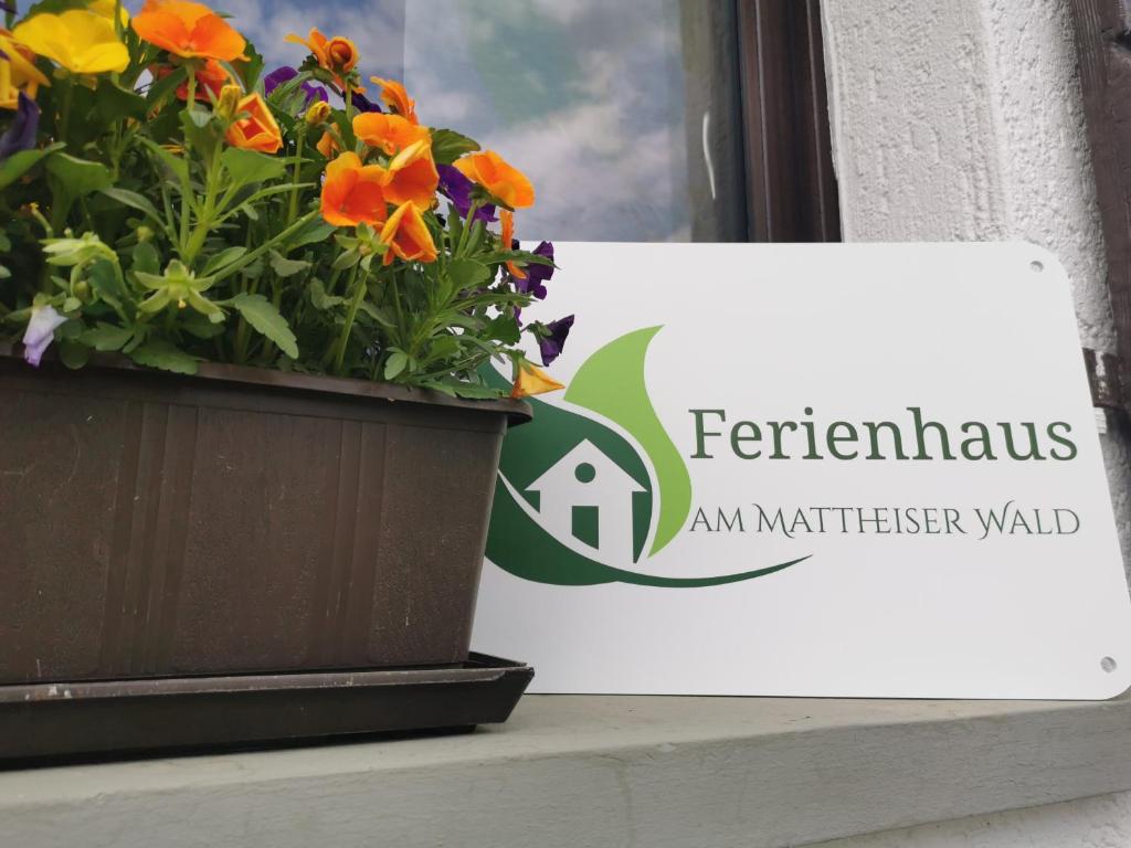 una pianta in vaso seduta sul davanzale di una finestra accanto a un cartello di Ferienhaus am Mattheiser Wald a Treviri