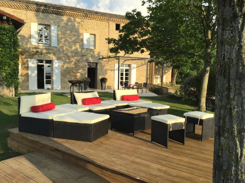 une terrasse en bois avec des canapés et des tables. dans l'établissement Agréable bastide provençale avec piscine, à Barcelonne