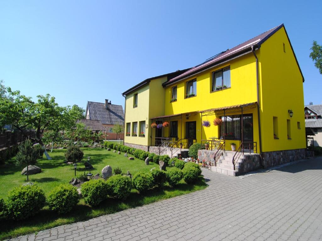 una casa amarilla con un jardín delante de ella en Pas Birutę, en Palanga