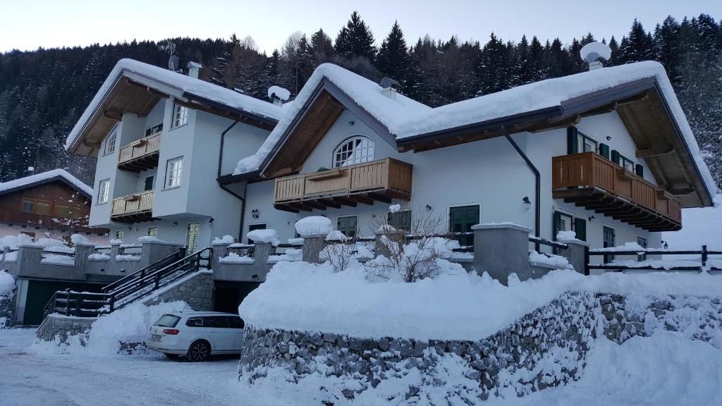 une maison recouverte de neige avec une voiture garée devant dans l'établissement Residenza Andreotti, à Ossana