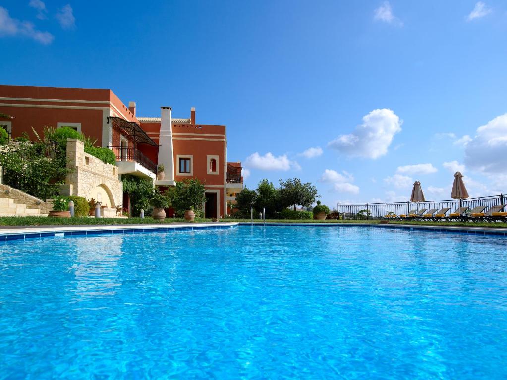 uma grande piscina azul ao lado de um edifício em Katalagari Country Suites em Archanes