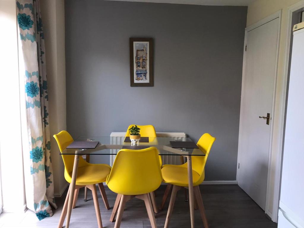 a dining room with a table and yellow chairs at Kettering Leisure Holiday Home in Kettering