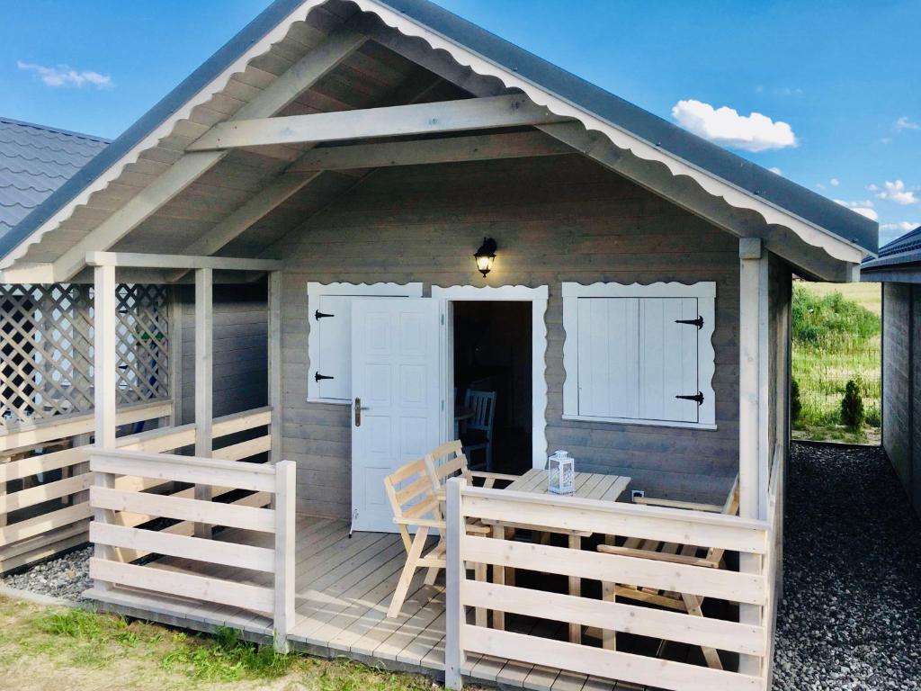 a house with a table and a chair on a deck at FHU Aquarius in Dziwnówek