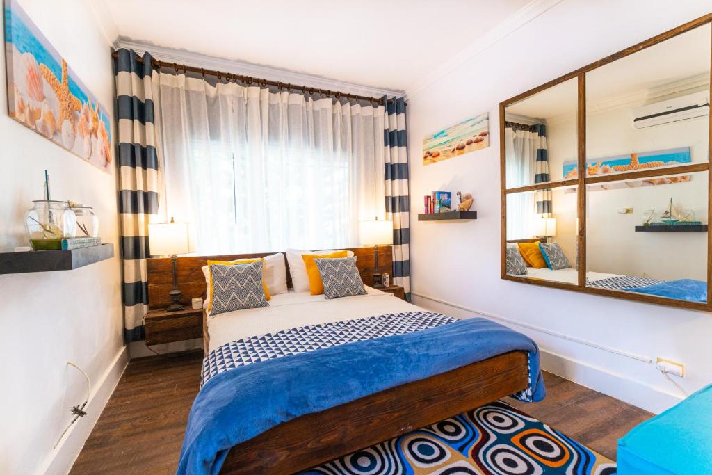 1 dormitorio con cama y espejo grande en Lemon Cottage - At Orange Hill, en Nassau
