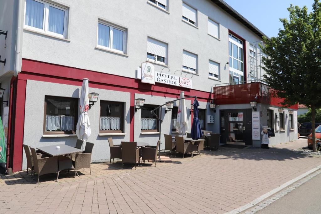 ein Gebäude mit Stühlen und Sonnenschirmen außerhalb des Gebäudes in der Unterkunft Hotel Loewen in Tübingen