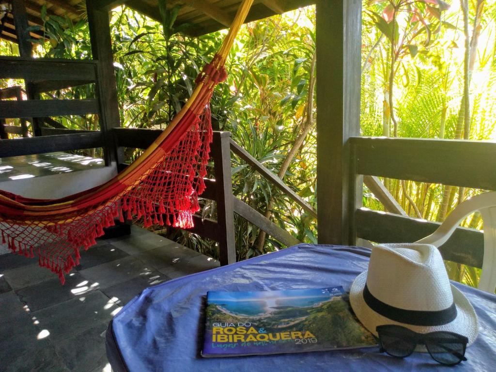 a hat and a book on a hammock on a porch at Morada Crisálida in Praia do Rosa