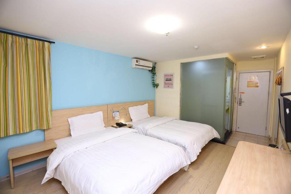 2 camas en una habitación de hotel con sábanas blancas en 7Days Inn Changsha Houjiatang Yali High School, en Changsha