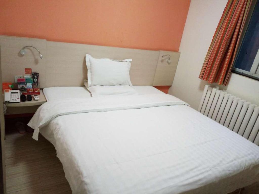 een groot wit bed in een kleine kamer bij 7days Inn·Zibo Zhoucun Taoyuan Ginza Branch in Zibo
