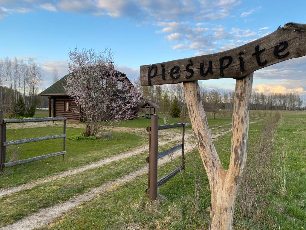um sinal de madeira que lê piscrift em um campo em Piešupīte em Staburags
