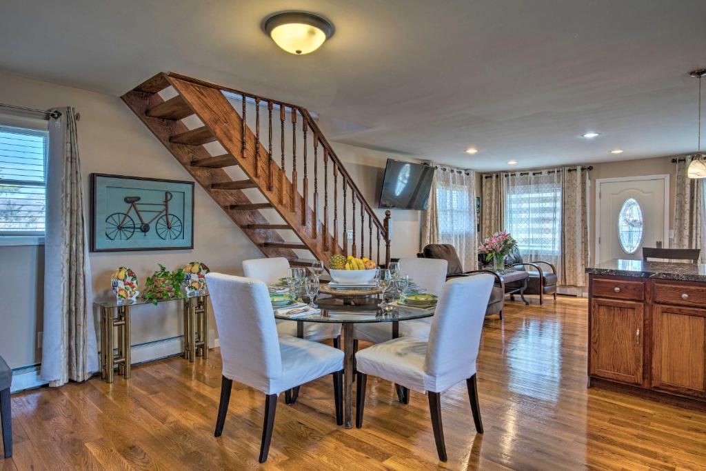 a dining room with a table and chairs and a staircase at Waterfront Home with Large Deck and Dock on Narrow Bay in Mastic Beach