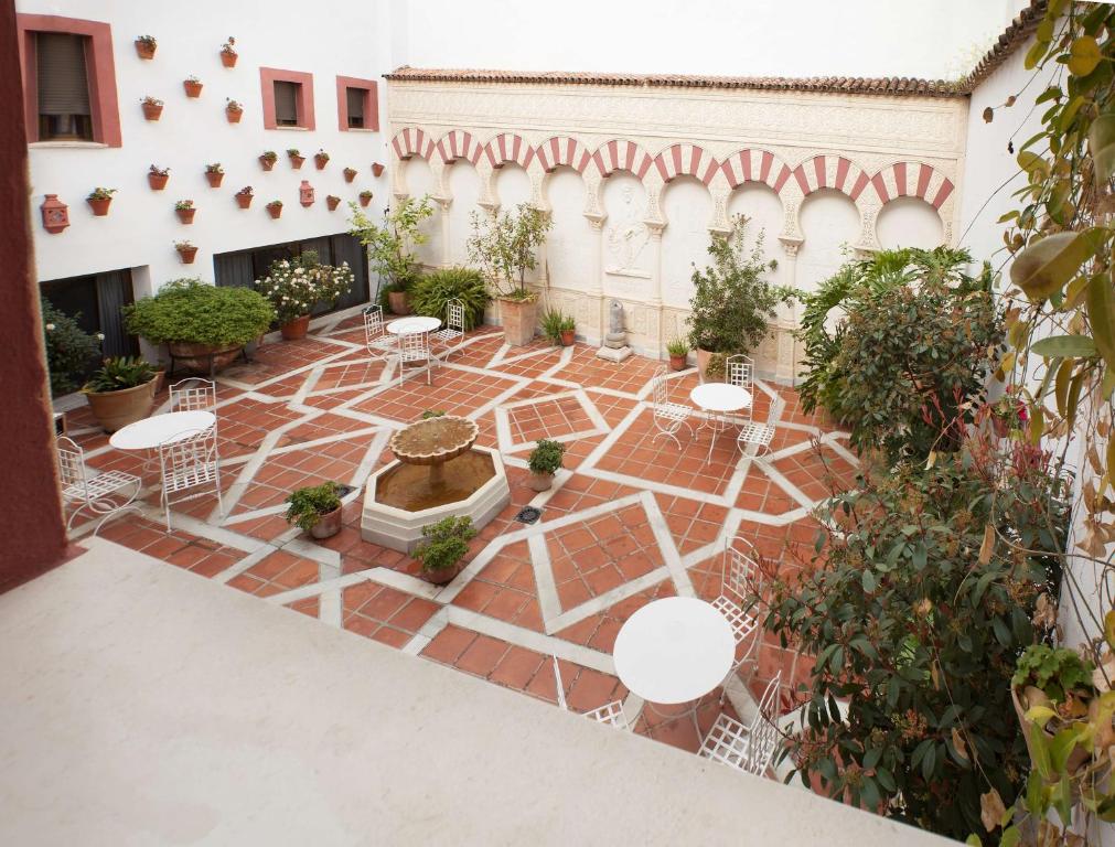 a courtyard with a fountain and tables and plants at NH Córdoba Califa in Córdoba
