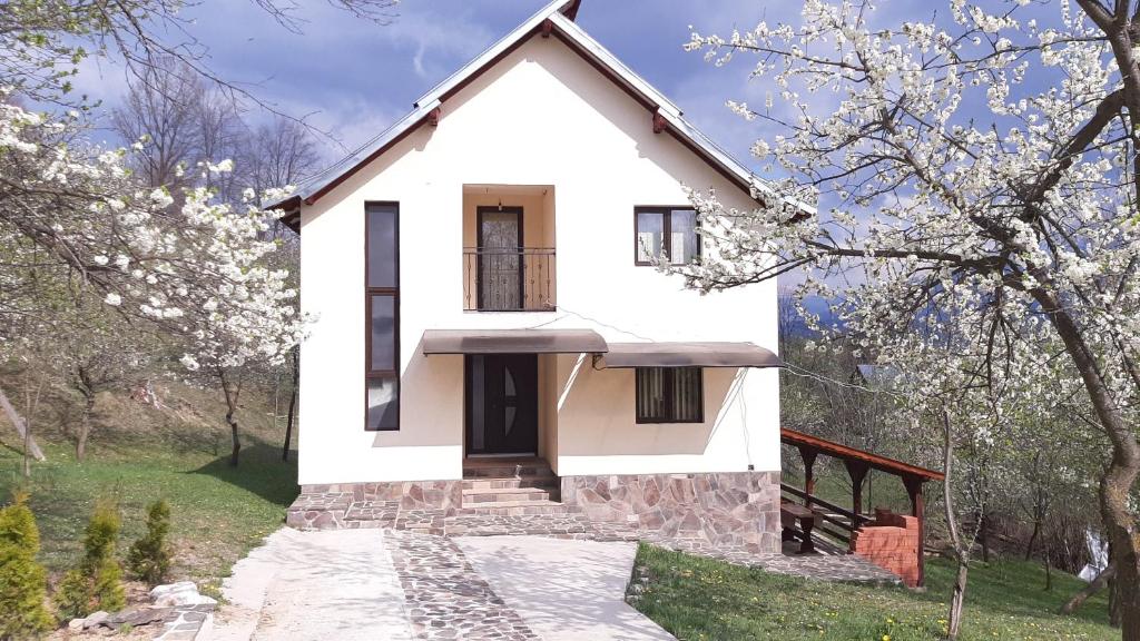 ein weißes Haus mit einem Tor und Bäumen in der Unterkunft Casa Fluțar in Moisei