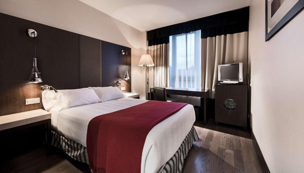um quarto de hotel com uma cama e uma televisão em NH Valladolid Bálago em Valladolid