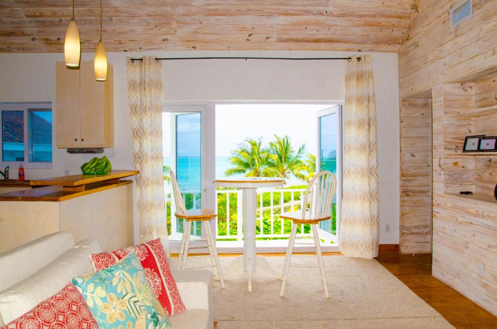 a living room with a couch and a kitchen with a balcony at Ocean View Cottage - At Orange Hill in Nassau