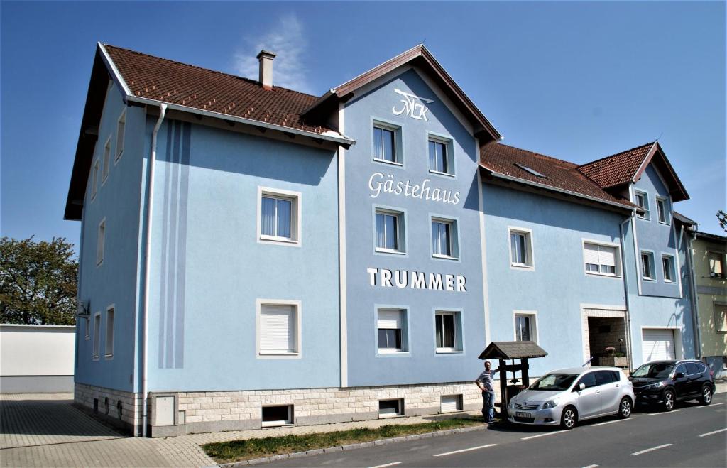 Gasthof & Gästehaus Trummer في Horitschon: مبنى ازرق فيه سيارات تقف امامه