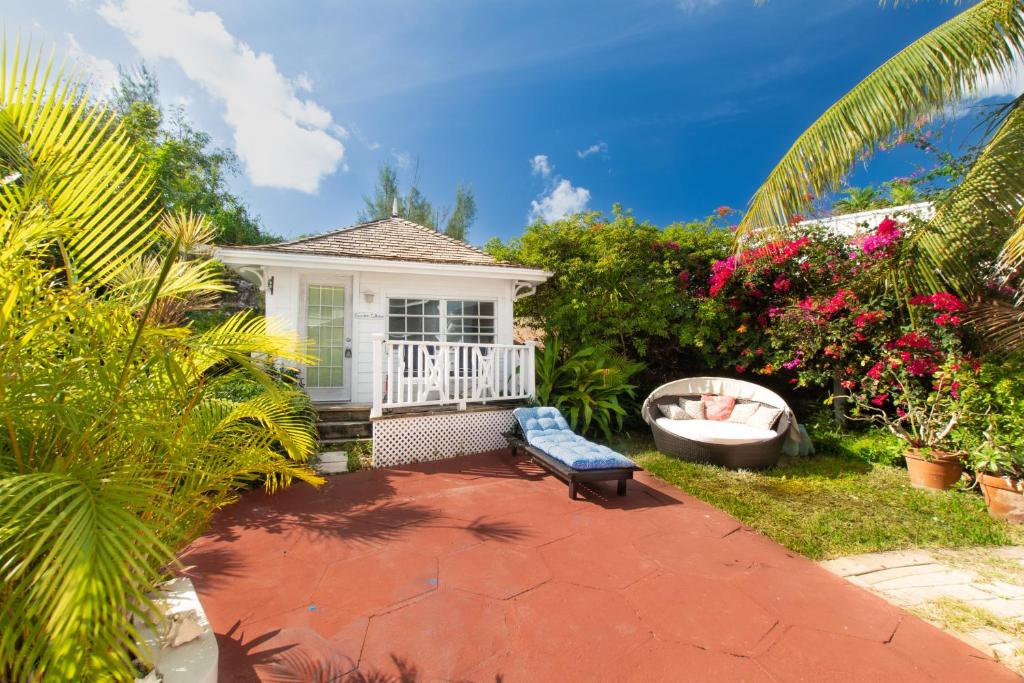 a house with a bench and a tub in the yard at Garden Cottage - At Orange Hill in Nassau