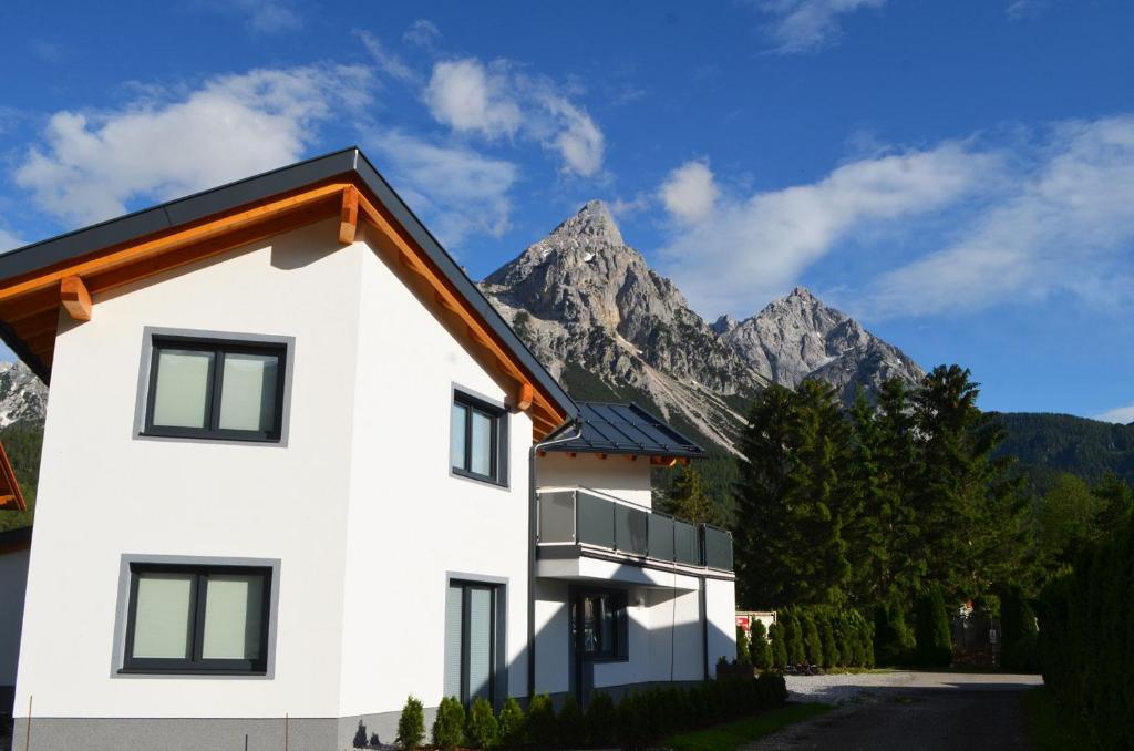 biały dom z górami w tle w obiekcie Zugspitzappartements w mieście Ehrwald