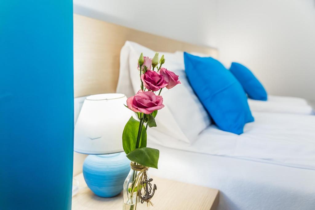 a vase with pink flowers on a table next to a bed at Kubryk in Rewa