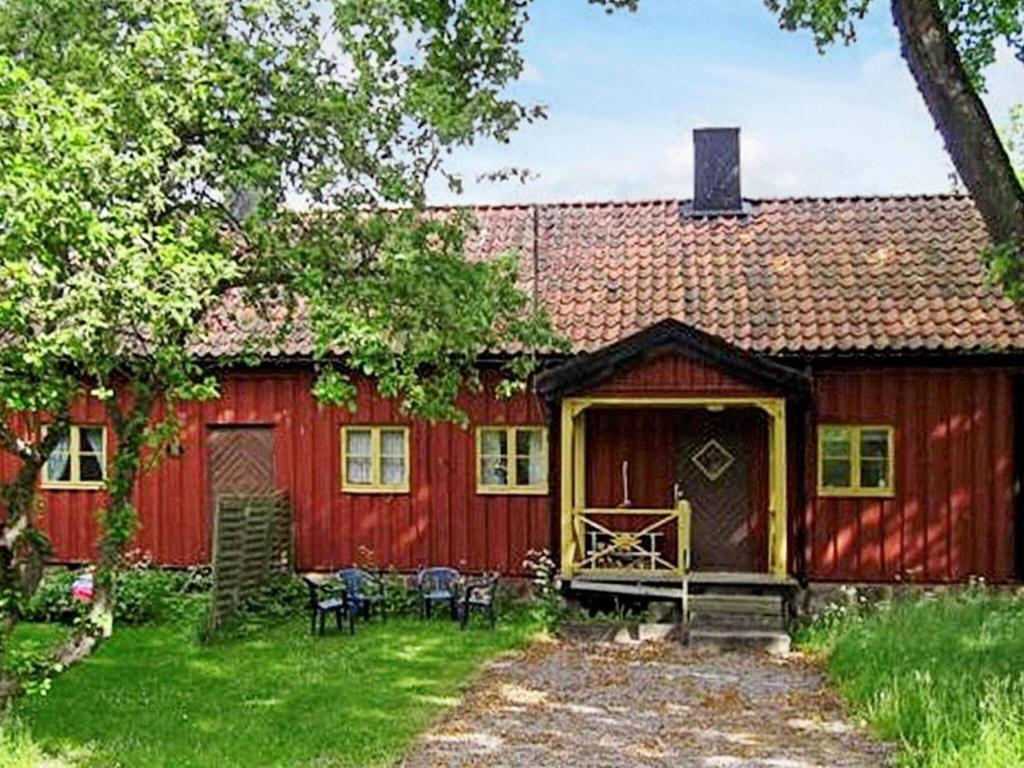 um celeiro vermelho com uma mesa e cadeiras em frente em 6 person holiday home in LOFTAHAMMAR em Loftahammar