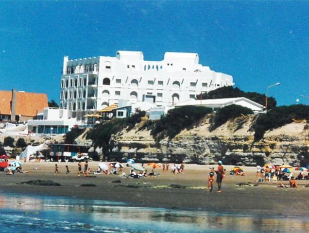 un grupo de personas en una playa con un gran edificio en Mirador Azul en Las Grutas