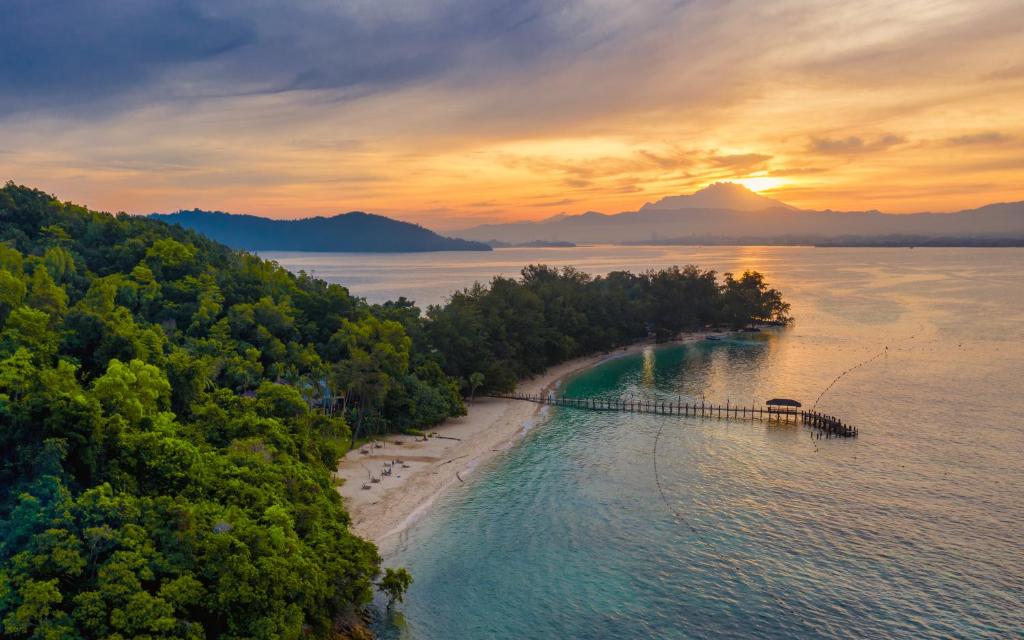 una isla en un cuerpo de agua con un muelle en Sutera Sanctuary Lodges At Manukan Island en Kota Kinabalu