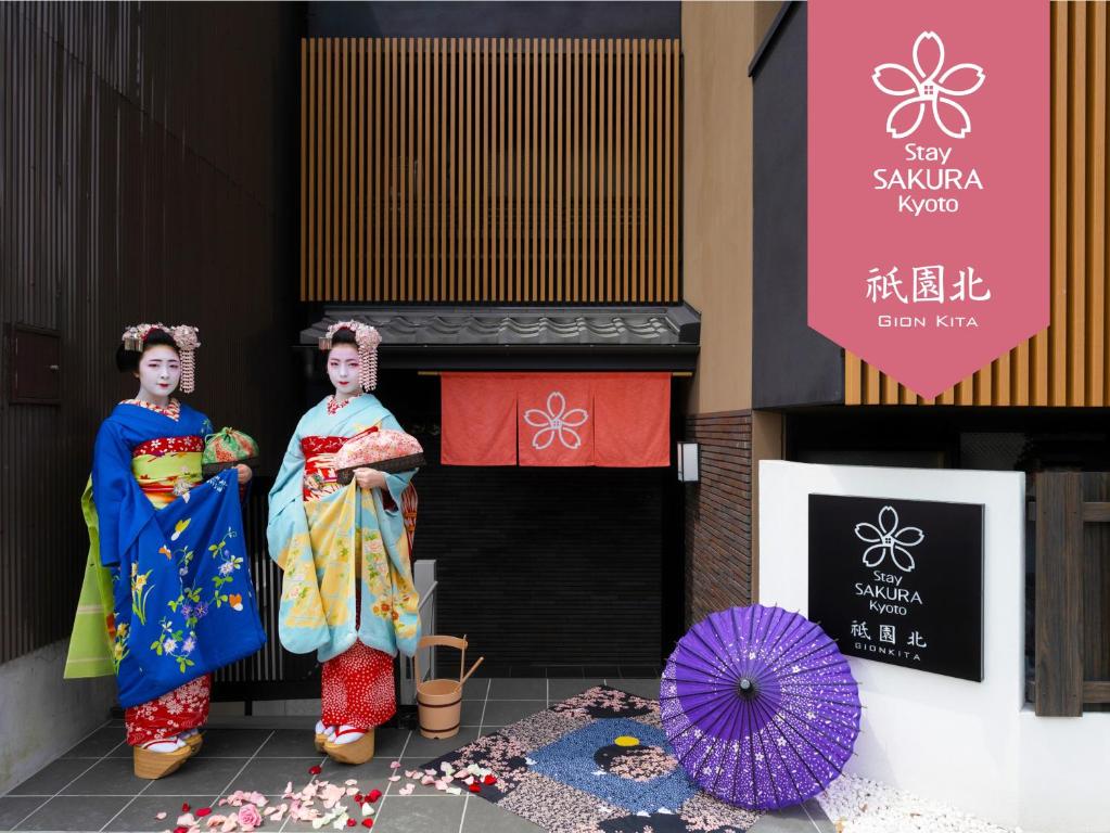 京都的住宿－Stay SAKURA Kyoto Gion North，两人和服站在一座建筑前