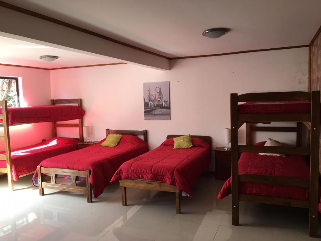 two beds in a room with red sheets at HOSTAL CAUQUENES in De Cauquenes