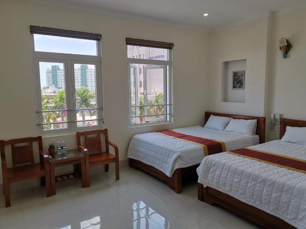 a bedroom with two beds and two windows at An Ngân Phú Hotel in Quy Nhon
