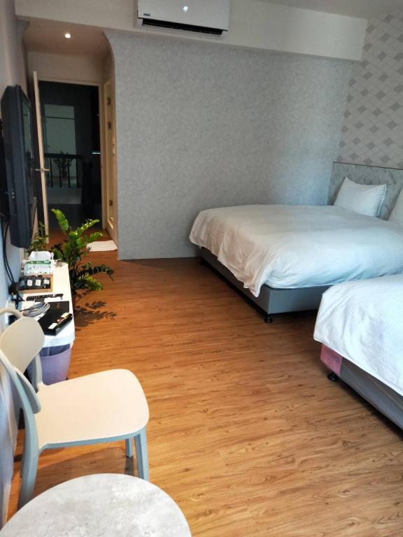 a room with two beds and a desk and a tv at Light Blue Hostel in Hengchun South Gate