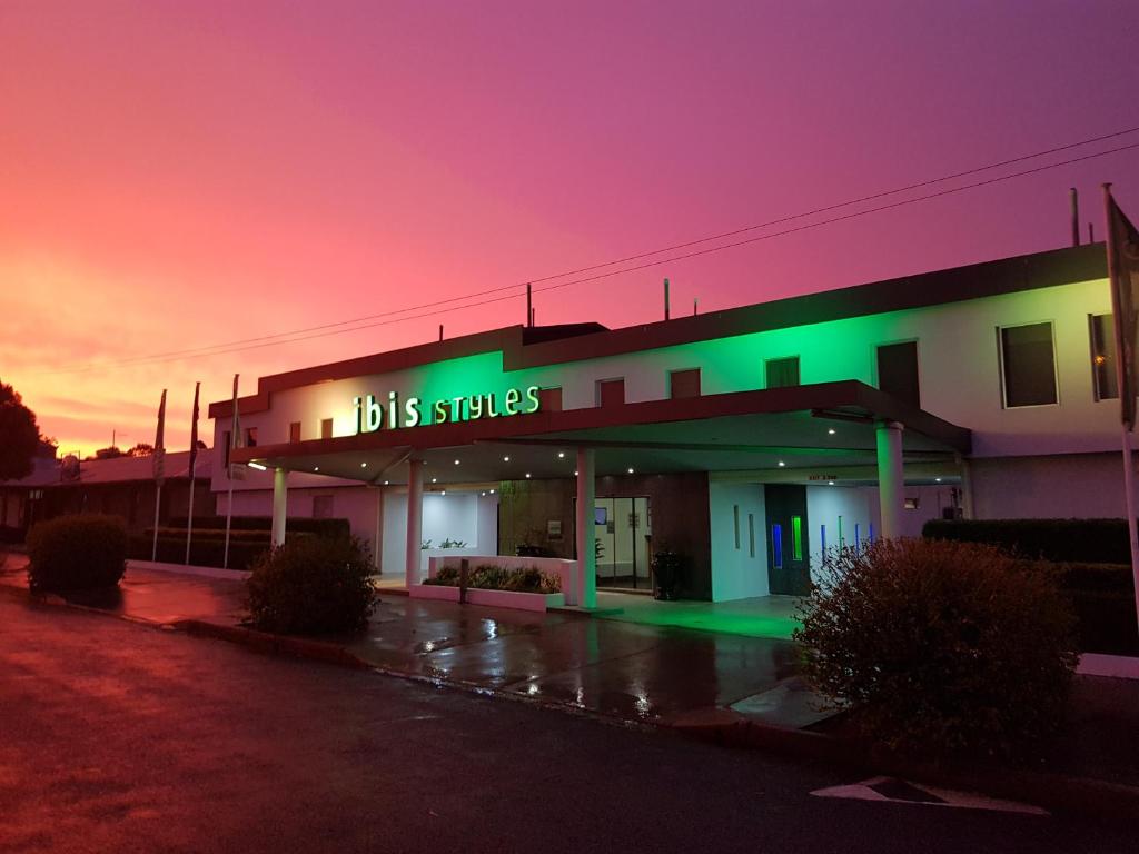 un edificio con un letrero verde en un estacionamiento en ibis Styles Broken Hill, en Broken Hill