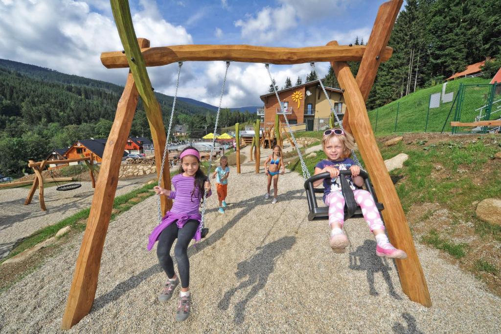 two children riding on a swing at a playground at Vetrnik Depandance Hotelu Jirinka in Dolní Morava